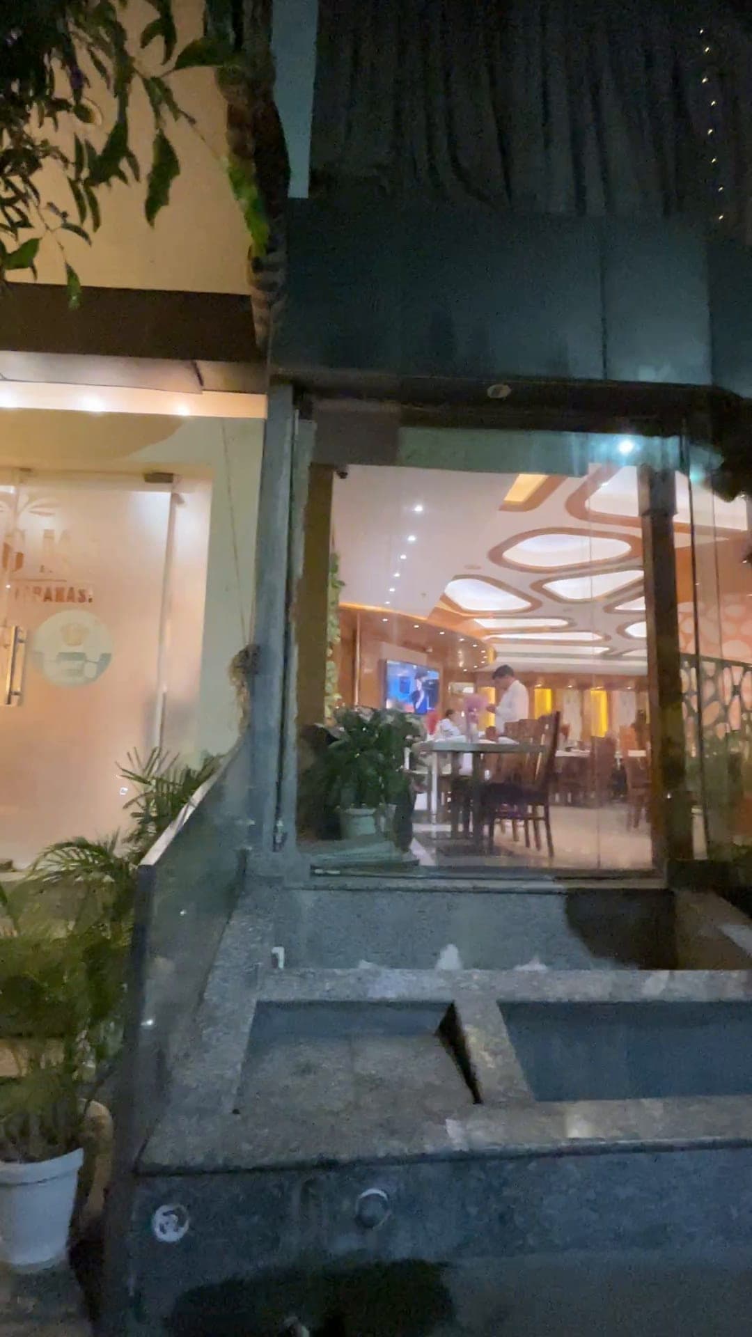 Hotel Vagmi lit at dusk - the glass frontage and the restaurant glowing within.