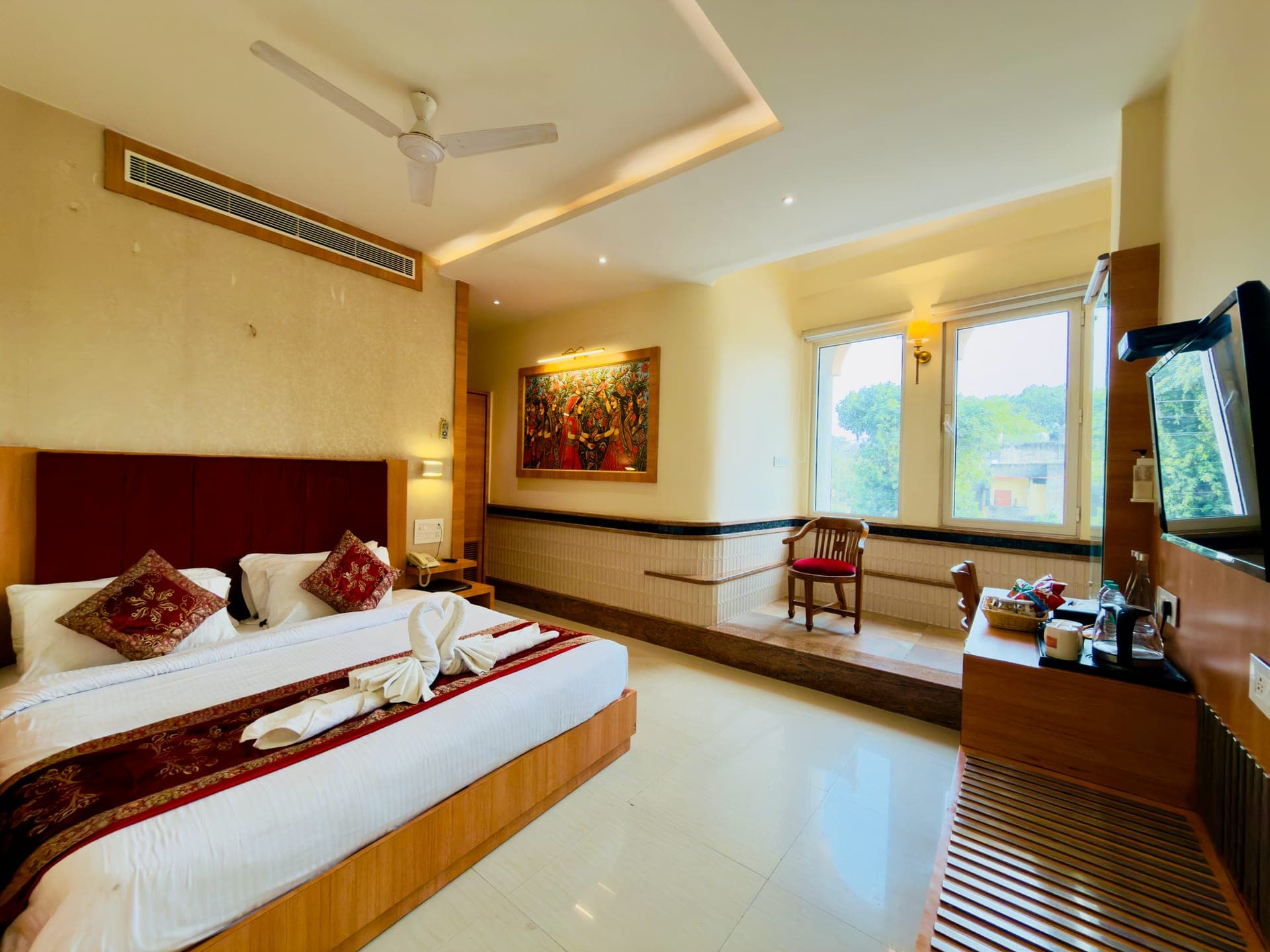 A Hotel Vagmi guest room - warm wood and a made bed by a bright window.