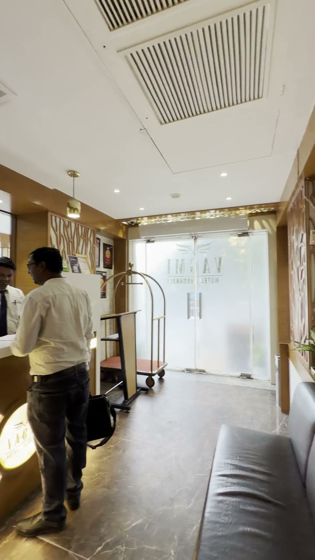 The lobby of Hotel Vagmi, Varanasi — frosted glass doors and a golden jaali screen