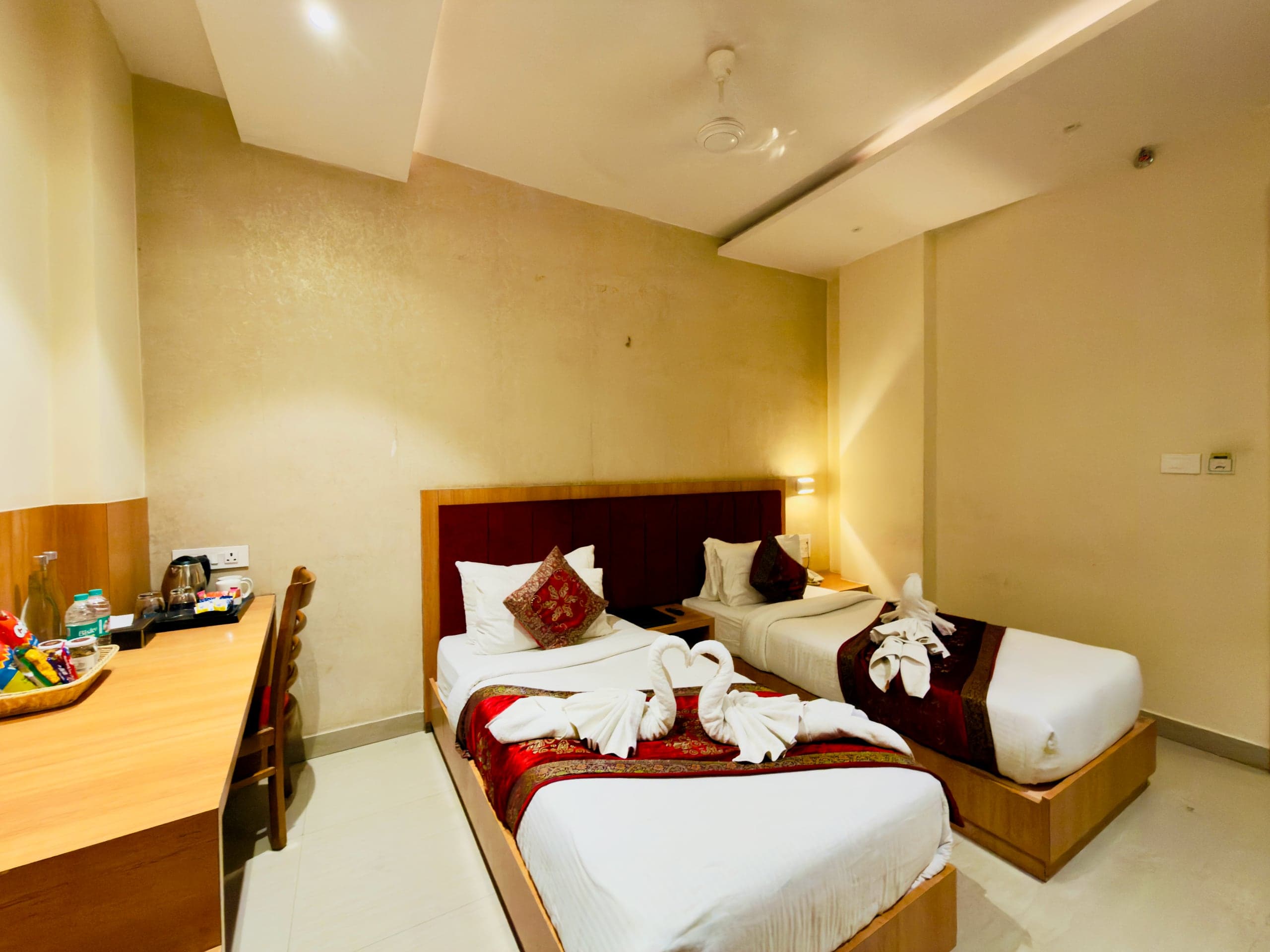 Deluxe Twin room at Hotel Vagmi - two single beds with crimson runners and towel swans