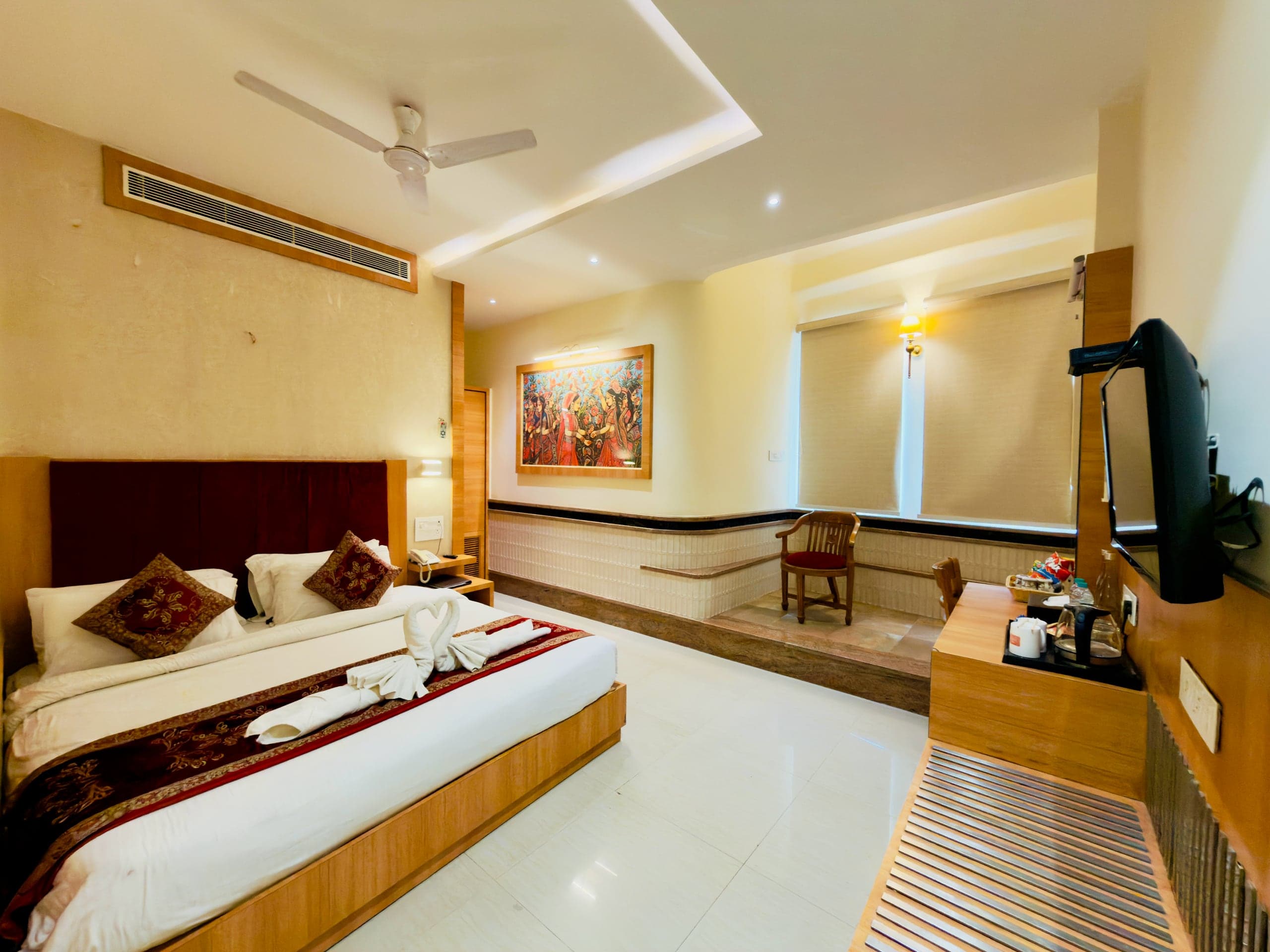 Executive room at Hotel Vagmi — king bed beneath a large Banarasi painting, tiled wainscot and window alcove