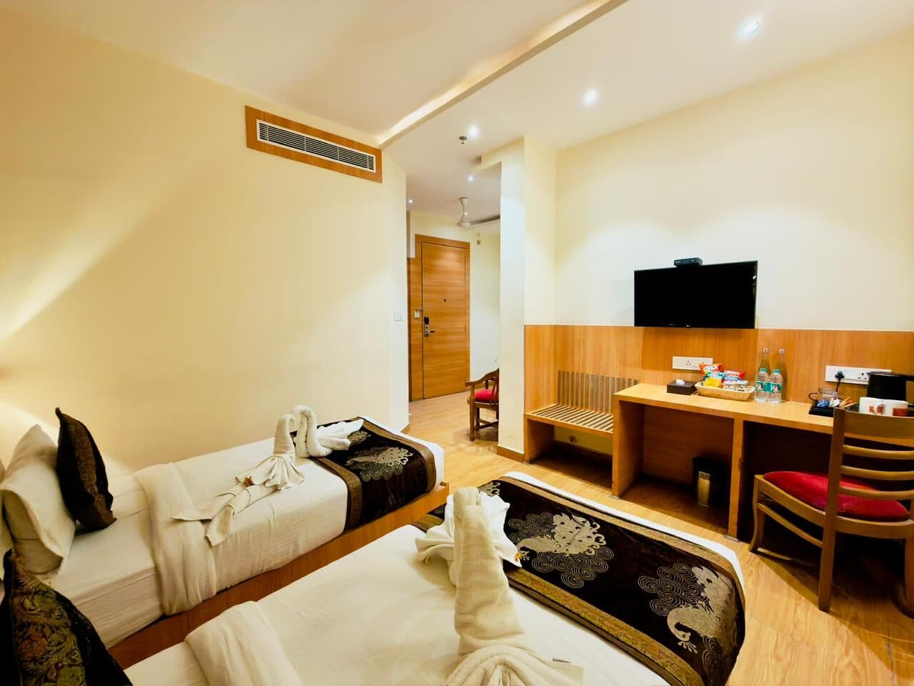 Mini Suite at Hotel Vagmi - warm wooden flooring, beds dressed in dark brocade runners, desk and wall-mounted TV