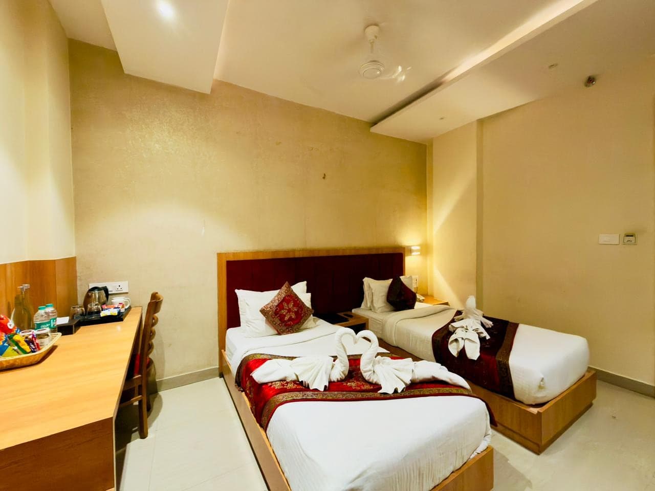 Deluxe Twin room, both single beds dressed in red Banarasi runners with hand-folded towel swans