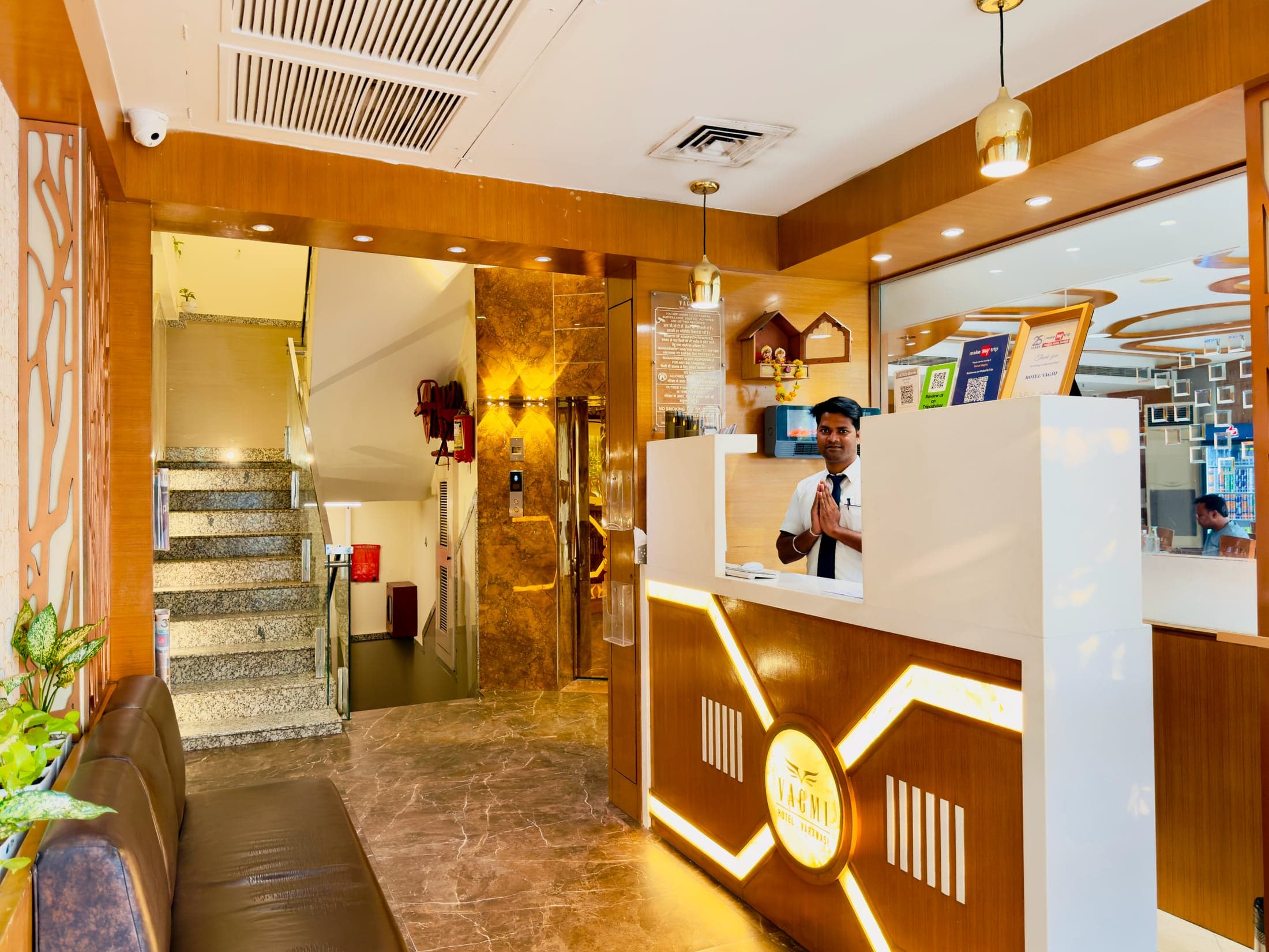 Reception at Hotel Vagmi - a staff member welcoming guests at the brass-lit front desk